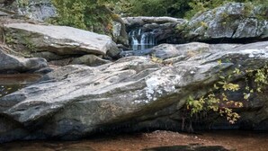A natural landscape with a waterfall, large rocks, and dense forest. - Luxury Spacious Glamping, Lake View, Grill, Pool, Pet Friendly, Swim (Delta)