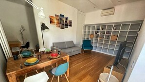 Een moderne woonkamer met een houten eettafel, stoelen, een bank, een boekenkast en een televisie.