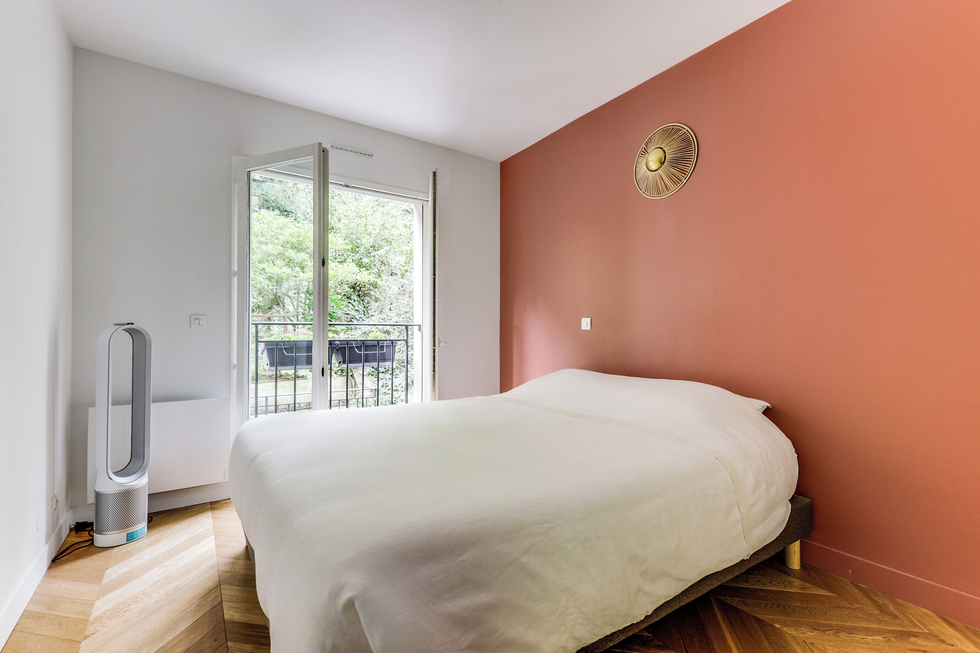 A bedroom with a bed, a heater, a window, and a view of greenery outside.