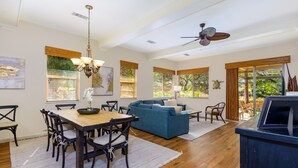 A spacious living area with a dining table, blue sofa, and a ceiling fan. - Fairways 402- Mauna Lani Resort-Private Beach Club Access-Golf Course Front-3 BR (Waimea)