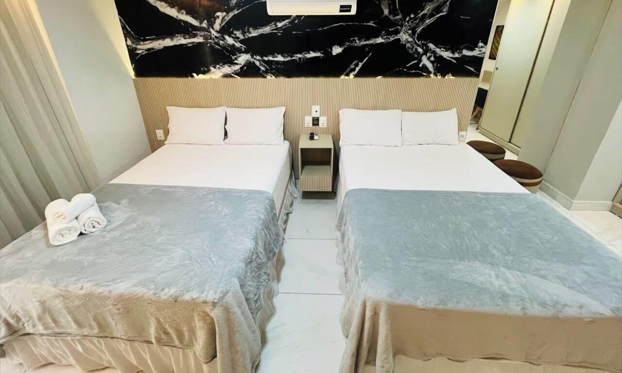 Une chambre d’hôtel avec deux lits, un mur en marbre et une table de chevet avec une lampe.