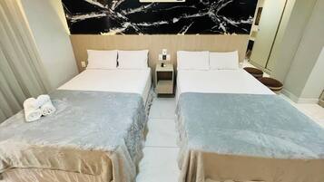 Une chambre d’hôtel avec deux lits, un mur en marbre et une table de chevet avec une lampe.