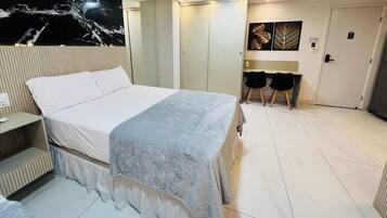 A bedroom with a bed, a desk, two chairs, and a wardrobe.