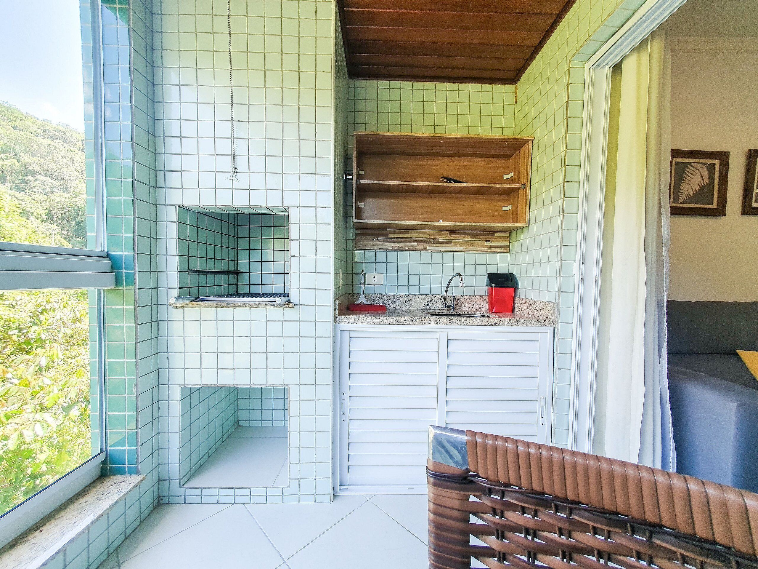 A compact kitchen with a window, a sink, and a wooden cabinet.