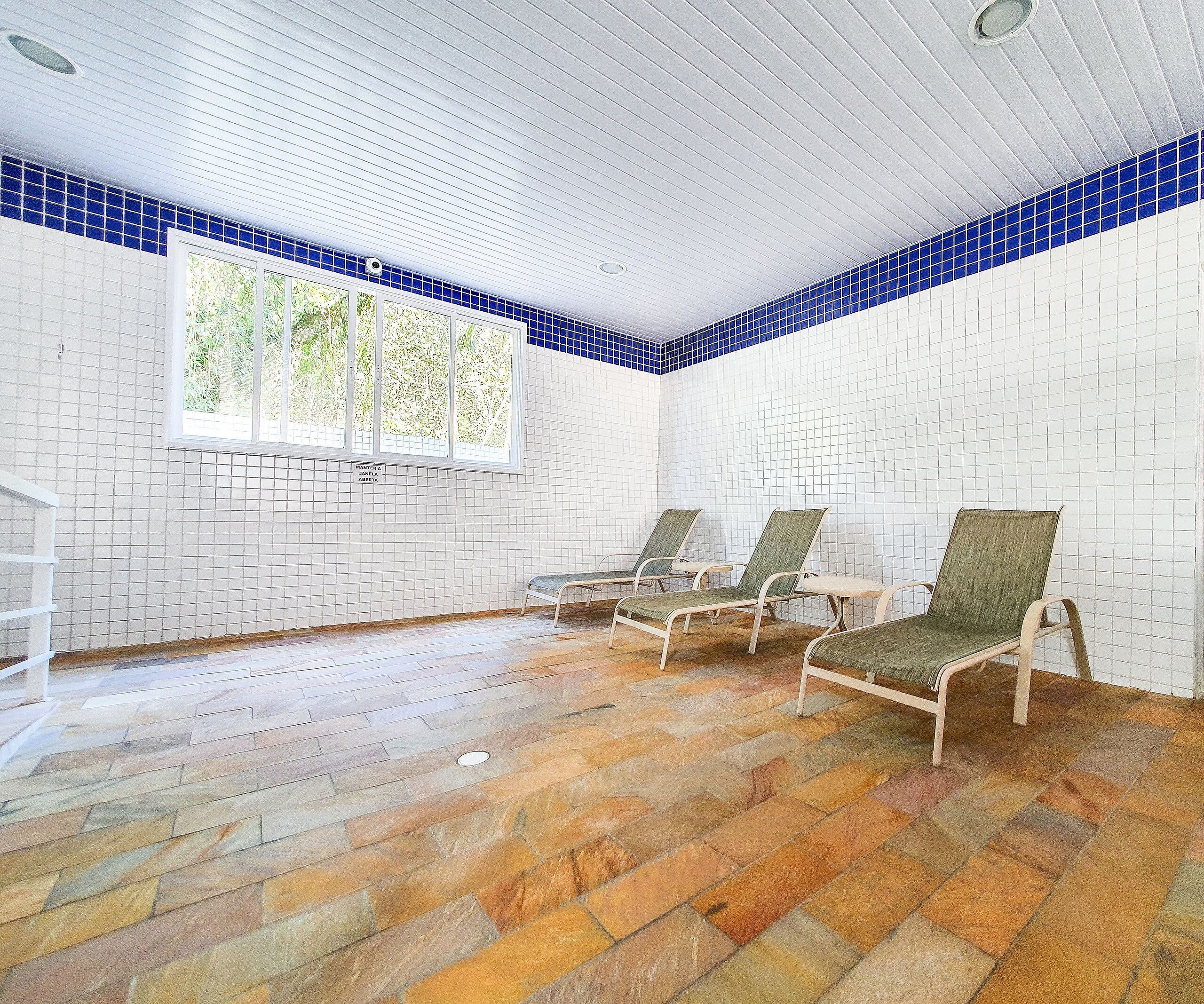 A room with a tiled floor, a window with a view, and three chairs.