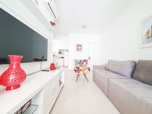 Una sala de estar moderna con un televisor de pantalla plana, un sofá gris y una silla colorida.
