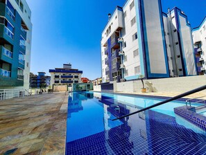Una piscina techada, una piscina al aire libre, sombrillas