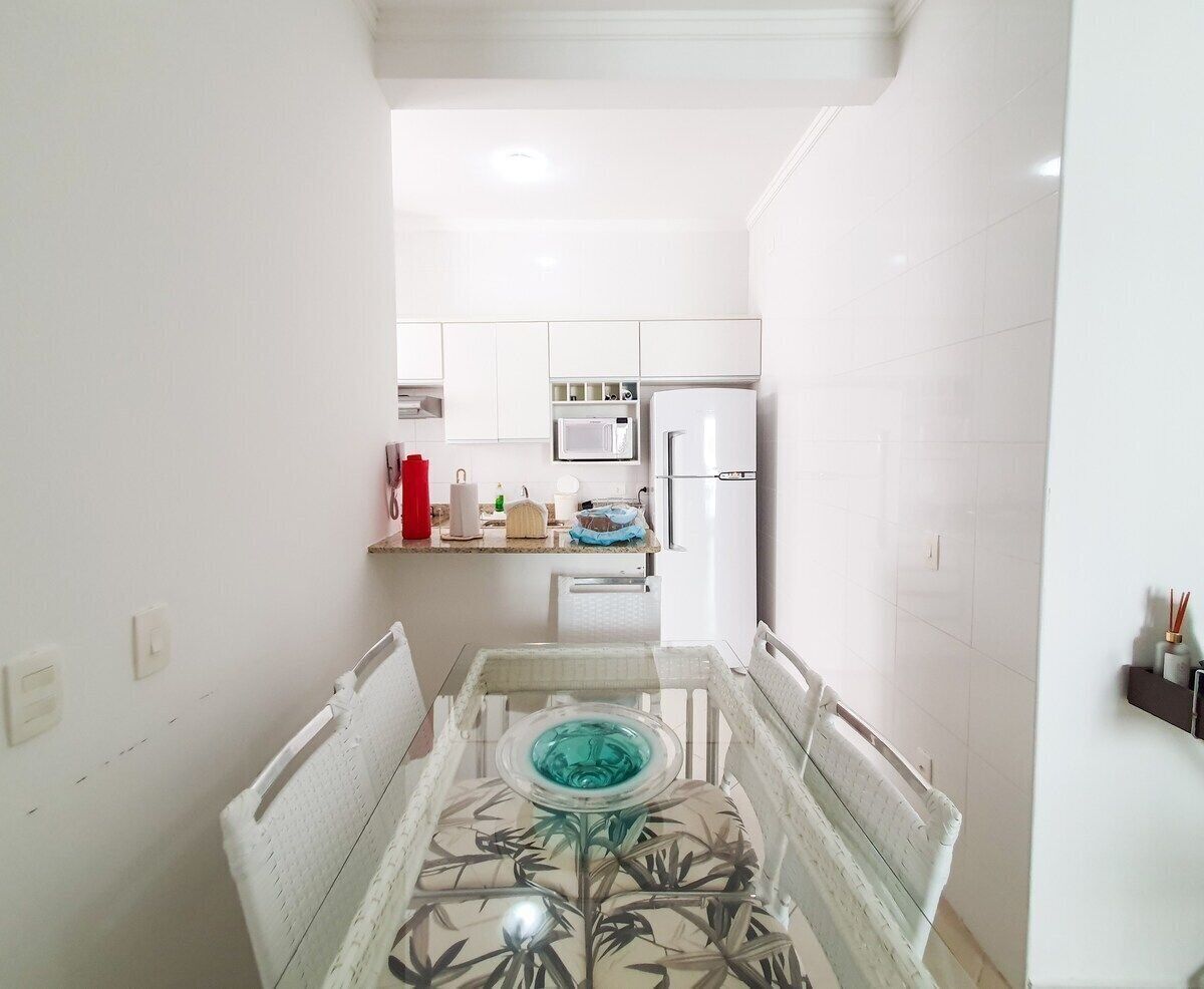 A narrow kitchen with white cabinets, a microwave, and a refrigerator.