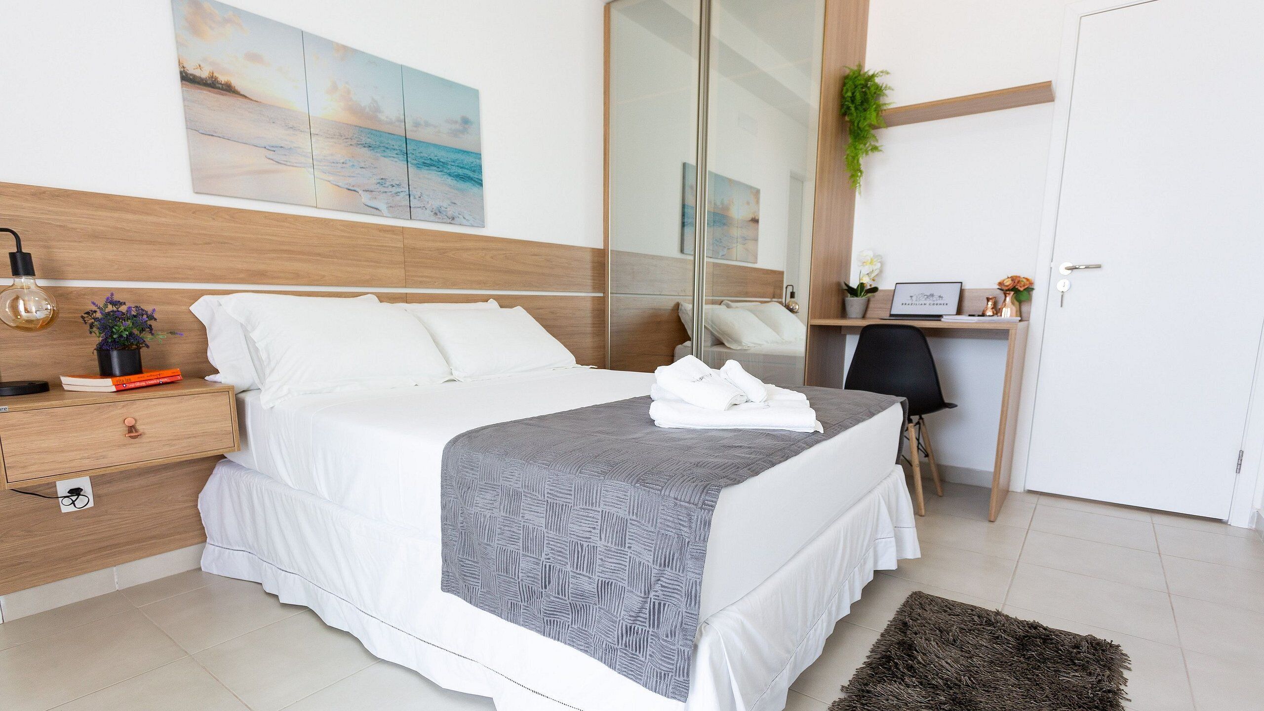A modern hotel room with a large bed, a desk, and a mirror.