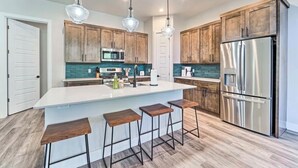Una cucina moderna con mobili in legno, elettrodomestici in acciaio inossidabile e un'isola centrale con sgabelli.