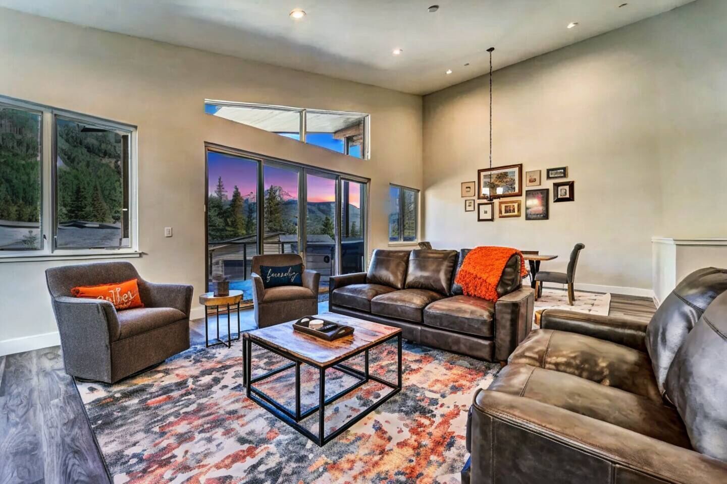 A spacious living room with leather sofas, a coffee table, and a large window offering a scenic view.