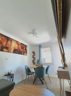 A modern living room with a dining area, a ceiling fan, and a large painting on the wall. - Appartement Climatisé en Maison Avec Terrasse Aménagée (Six-Fours-les-Plages)