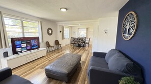 A modern living room with a flat-screen TV, a sofa, a bench, and a dining area with chairs. - Miami 3BR | Walk to LoanDepot Park | Patio (Miami)