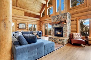 L’intérieur d’une cabane en rondins, avec une cheminée en pierre, un canapé bleu et un fauteuil rouge.