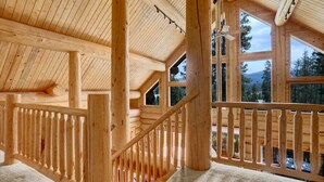 A wooden cabin interior with a balcony, large windows, and a ceiling fan. - Indulge | Majestic Views | Tipi | Hot Tub - Sauna (Winter Park)
