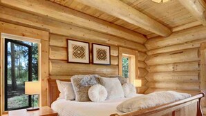 A wooden cabin bedroom with a bed, nightstands, and framed artwork on the wall. - Indulge | Majestic Views | Tipi | Hot Tub - Sauna (Winter Park)