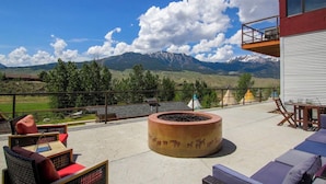 Una terraza con mobiliario exterior, una chimenea y vistas a las montañas.