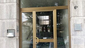 Une entrée d’immeuble avec une porte en verre, une main courante en métal et un marchepied en marbre.