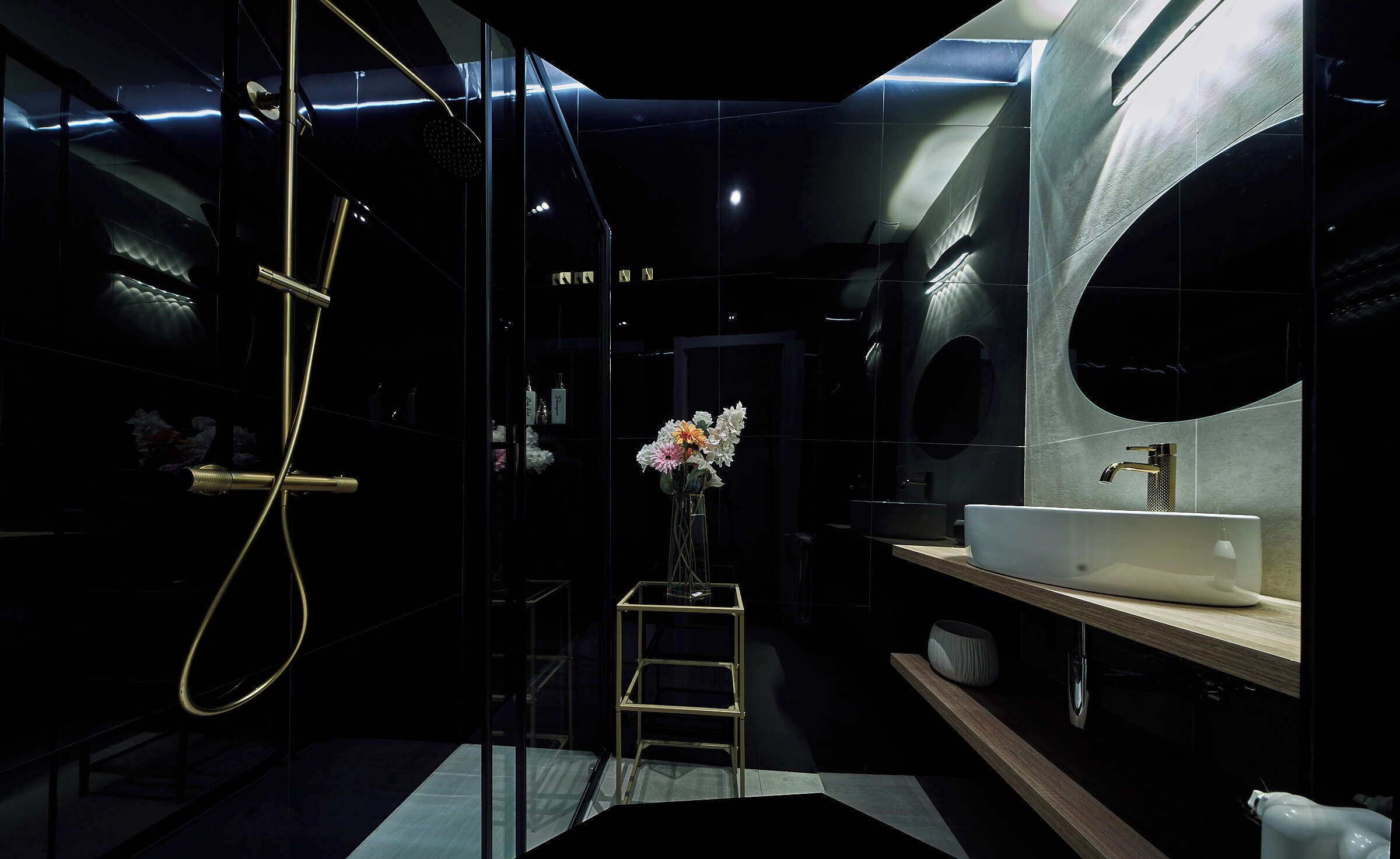 Ein modernes Badezimmer mit Duschkabine aus Glas, einem weißen Waschbecken und einem kleinen Holzschemel.