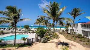 A resort with a swimming pool, palm trees, and a view of the ocean.