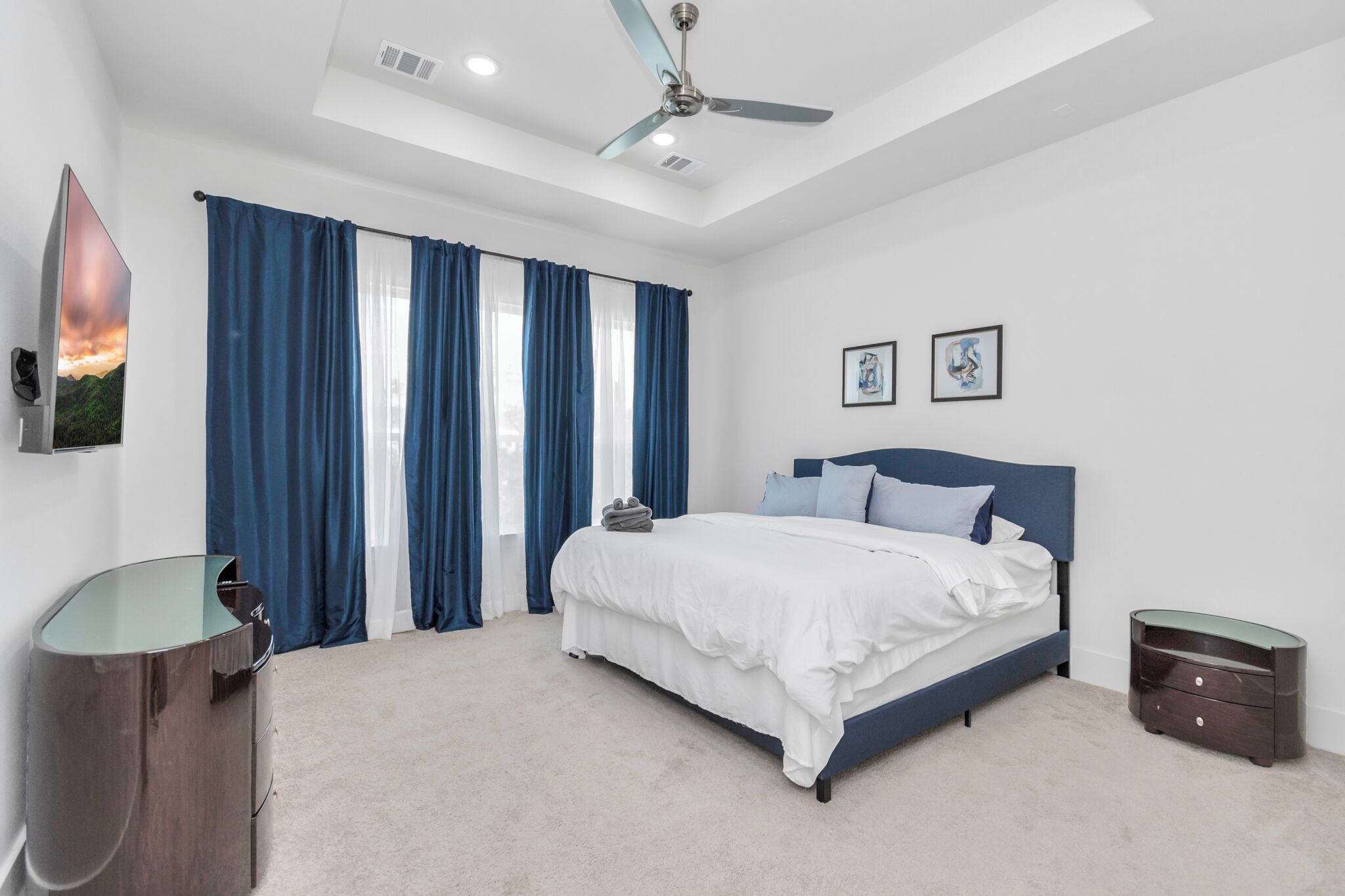 Un dormitorio con cama, mesita de noche, escritorio y ventilador de techo.