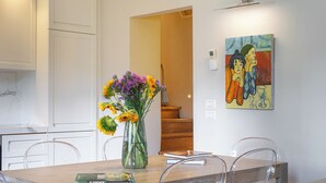 A dining area with a wooden table, clear chairs, a vase with flowers, and a painting on the wall. - Steps to Ponte Vecchio.3BR/3BA+terrace w view of Pitti Palace (Firenze)