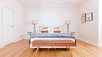 A bedroom with a bed, two bedside tables, a floor lamp, a headboard with a geometric design, and two framed pictures on the wall.