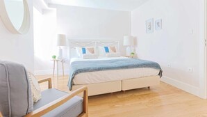 Ein modernes Schlafzimmer mit einem Bett, Nachttischen, einem Sessel und einem großen Spiegel.