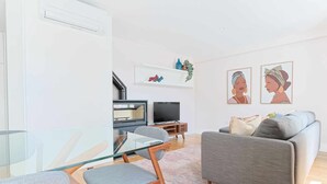 Ein modernes Wohnzimmer mit einem Glastisch, einem grauen Sofa und einem Flachbildfernseher.