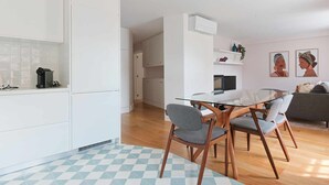 Eine moderne Küche mit weißen Schränken, einer Kaffeemaschine und einem Glastisch mit Stühlen.