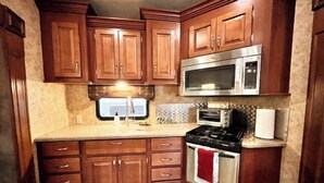 Una cocina con armarios de madera, un microondas de acero inoxidable, una estufa y una ventana con vistas.