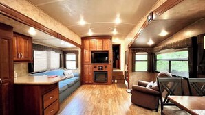 Interior compacto de una caravana con kitchenette, zona de estar y comedor.