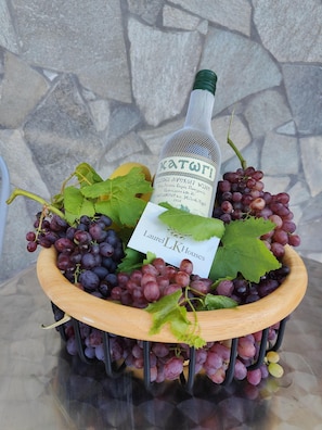 A wooden bowl filled with grapes and a bottle of wine, with a label that reads "Laurel LK Houses".