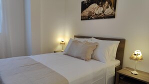 A neatly made bed with a patterned bedspread, two bedside lamps, and a painting on the wall. - Laurel LK Apt in Kremasti Near Airport Rhodes (Rhodes)