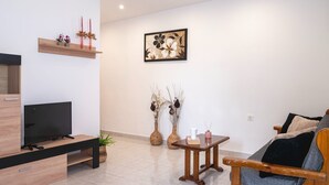 A modern living room with a TV, wooden furniture, a painting, and decorative vases. - Laurel LK Apt in Kremasti Near Airport Rhodes (Rhodes)
