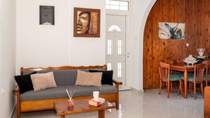 A living room with a wooden sofa, a coffee table, and a dining area with wooden chairs and a table. - Laurel LK Apt in Kremasti Near Airport Rhodes (Rhodes)