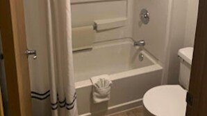 A bathroom with a bathtub, toilet, and shower curtain. - GO2 Inn & Suites by Relianse  (El Paso)