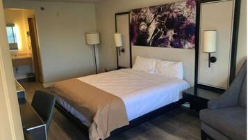 A hotel room with a bed, bedside lamps, a desk, and a chair.