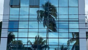 A modern building with a reflective glass facade, large windows, and a white exterior. - Melhores Flats (João Pessoa)