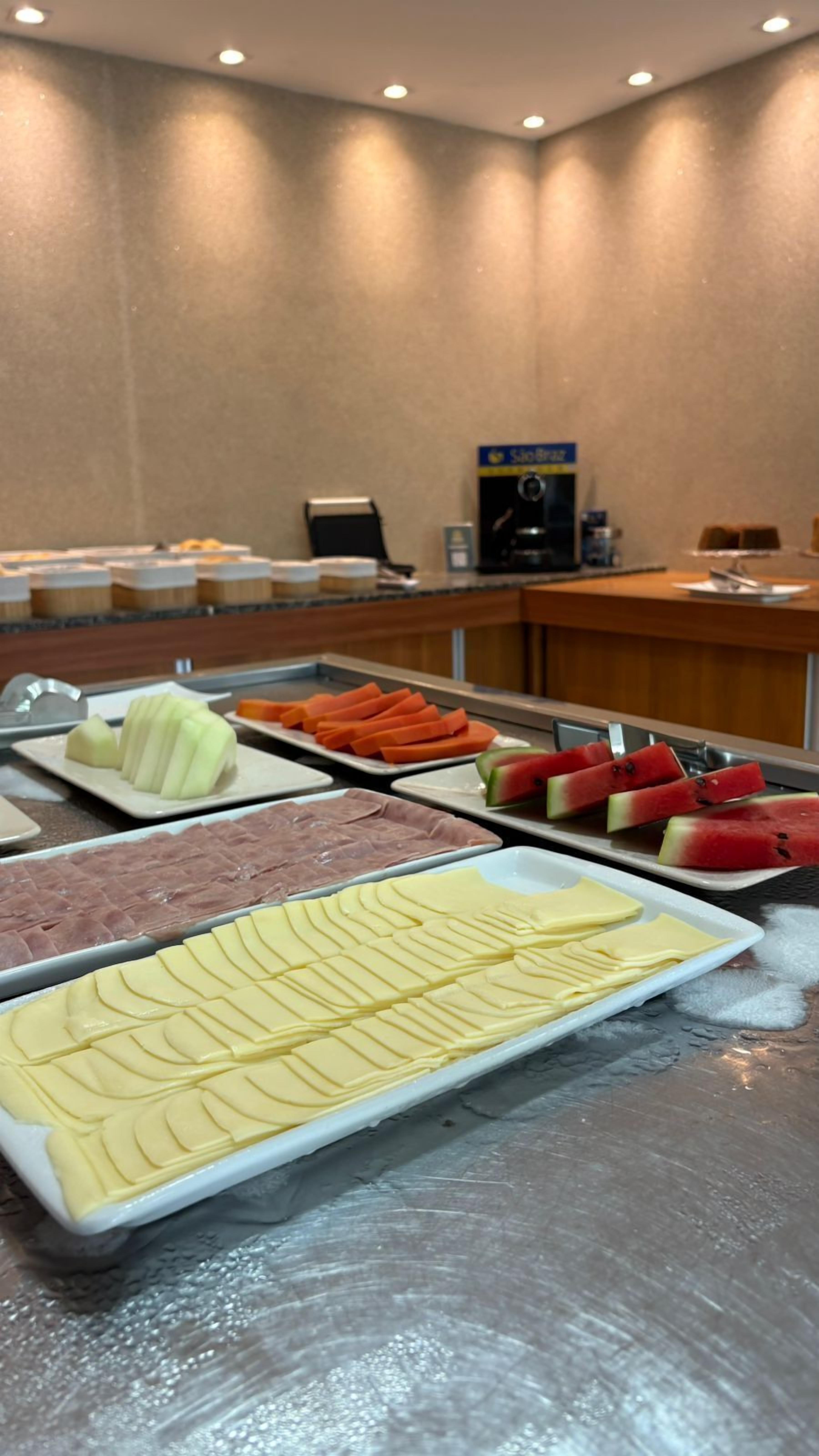 A buffet with various food items including sliced fruits, meats, and cheese.