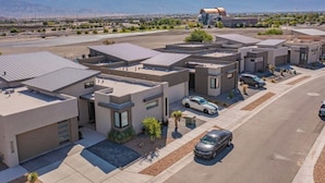 A modern residential area with detached houses, a parking lot, and a large building with a curved roof. - Balloon Fiesta: Rooftop Deck, Hot Tub, Sunsets (Albuquerque)