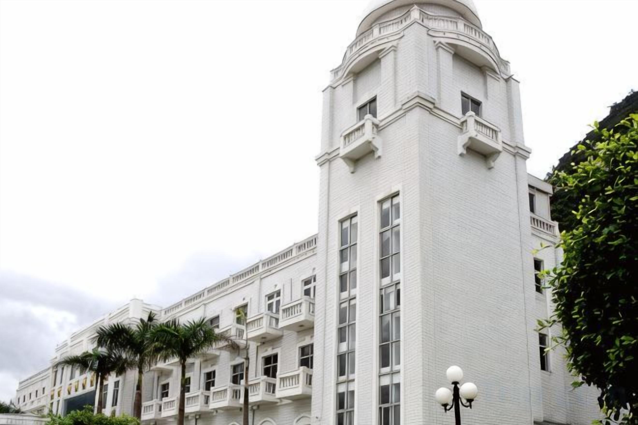 Un edificio de varios pisos con una torre angular destacada y balcones.