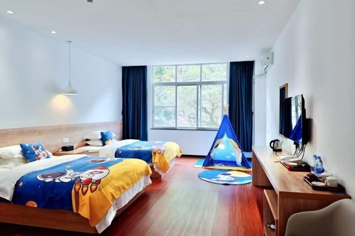 Une chambre d’hôtel avec deux lits, un bureau, une chaise, une tente et une grande fenêtre.