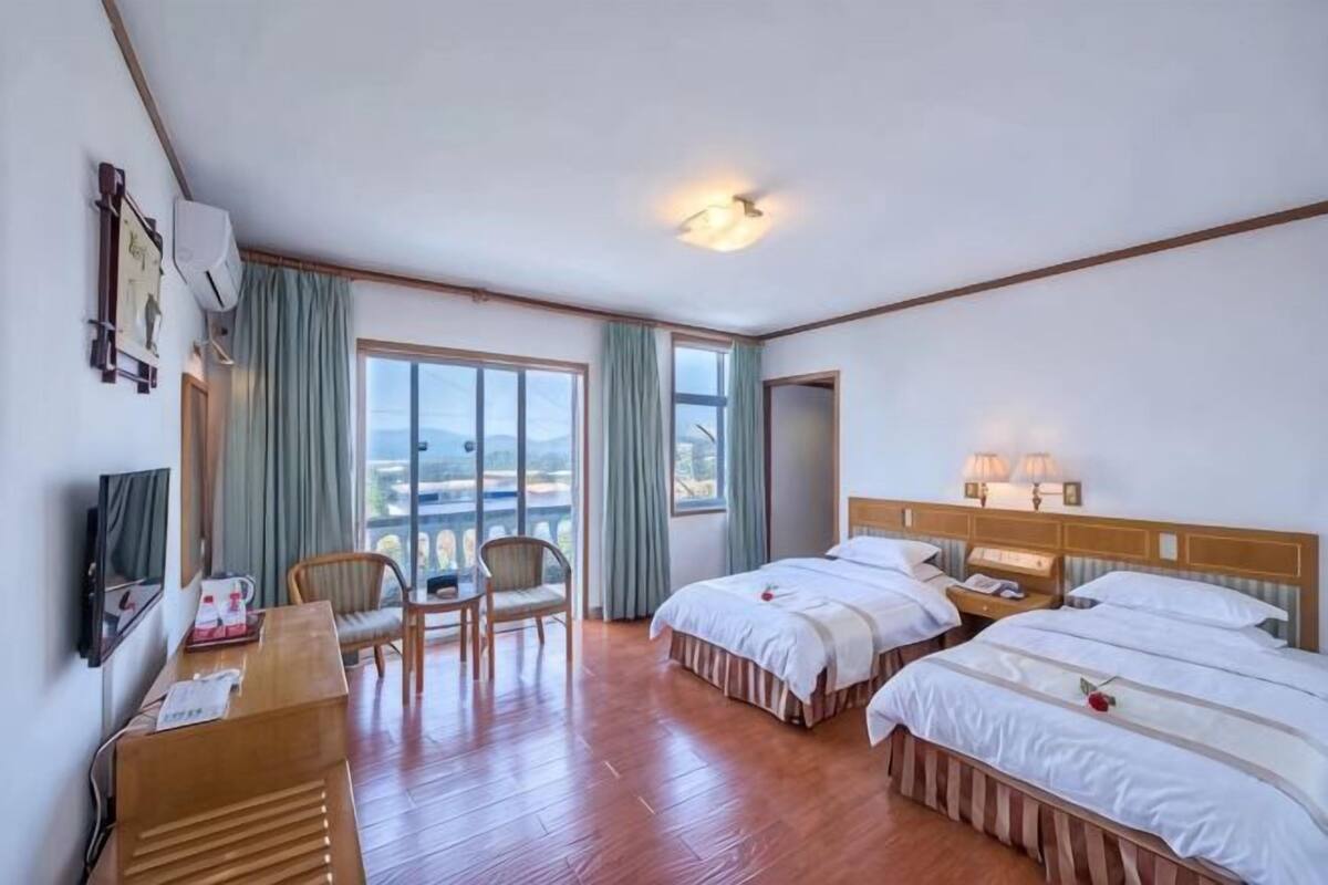 Une chambre d’hôtel avec deux lits, un bureau, une chaise et un téléviseur.