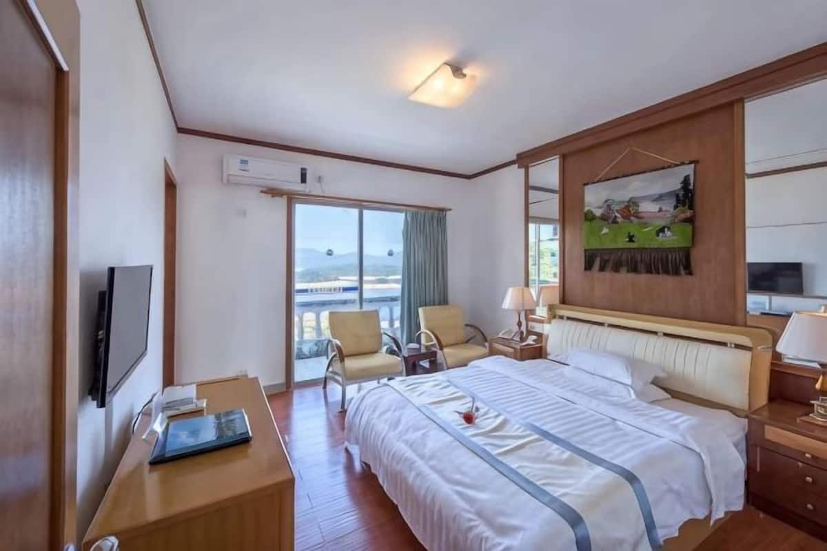 Une chambre d’hôtel avec un lit, un bureau avec un ordinateur portable, une chaise, une télévision et une fenêtre donnant sur un paysage agréable.