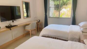 A hotel room with two beds, a desk with a chair, a television, and a window with curtains.