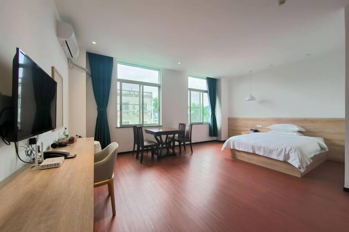Une chambre d’hôtel avec un lit, un bureau équipé d’un ordinateur, une chaise, une télévision et de grandes fenêtres.