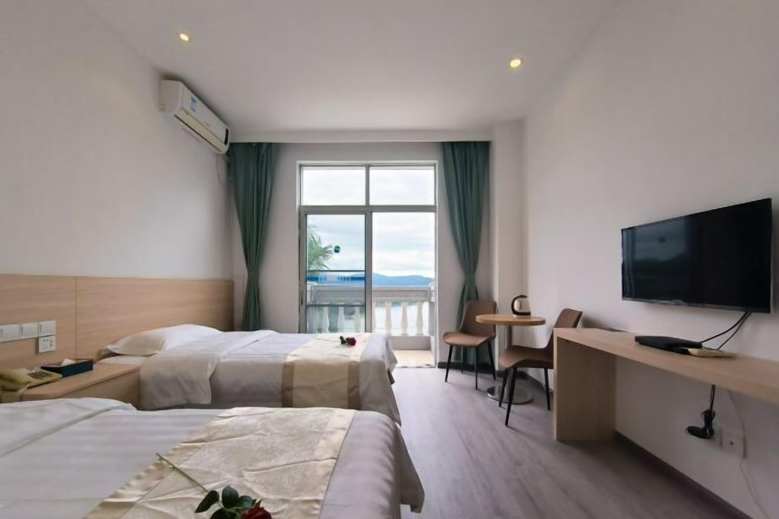 A hotel room with two beds, a TV, a desk, and a balcony with a view.