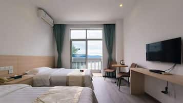 A hotel room with two beds, a TV, a desk, and a balcony with a view.