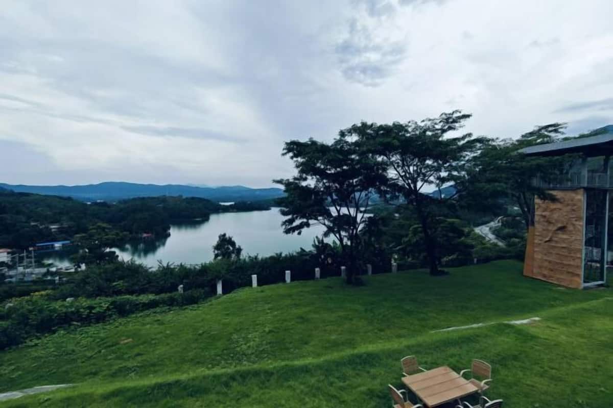 Un espace extérieur verdoyant, avec une table et des chaises, offrant une vue sur un lac et des collines.